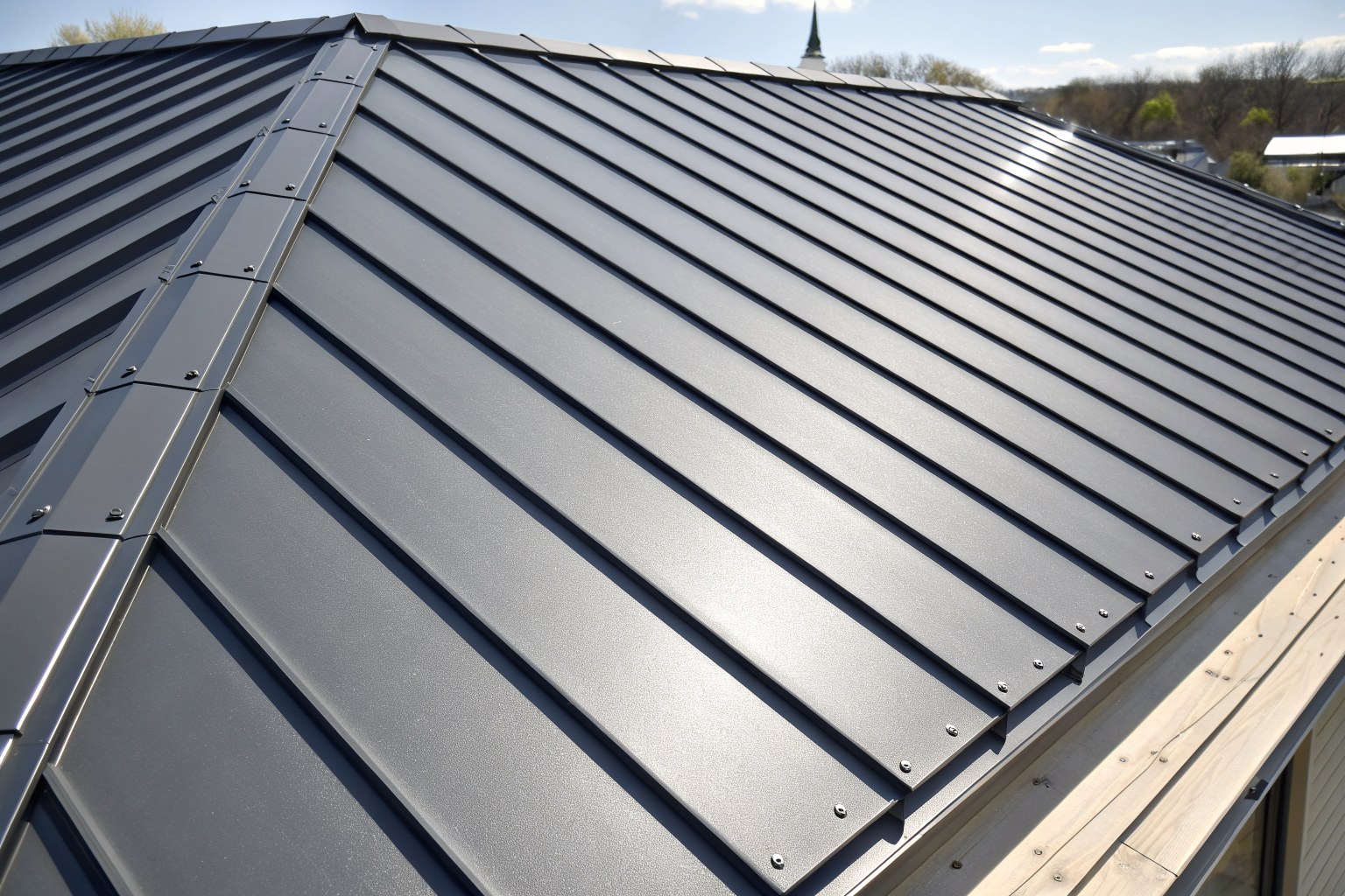 Close view of dark gray standing-seam metal roof panels in sunlight